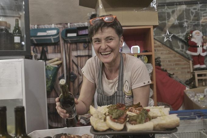 Una vendedora sonriente detrás del mostrador sirve pasteles en una vitrina de panadería.