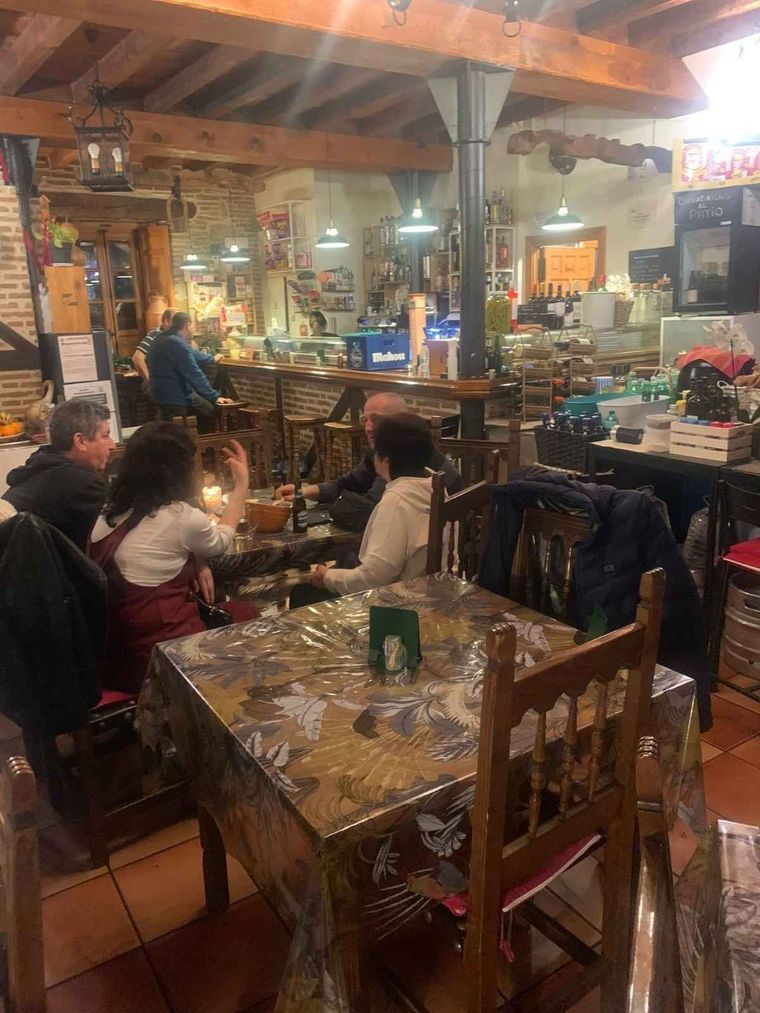 Acogedor restaurante rústico con comensales en mesas iluminadas con velas y un cálido techo de madera.