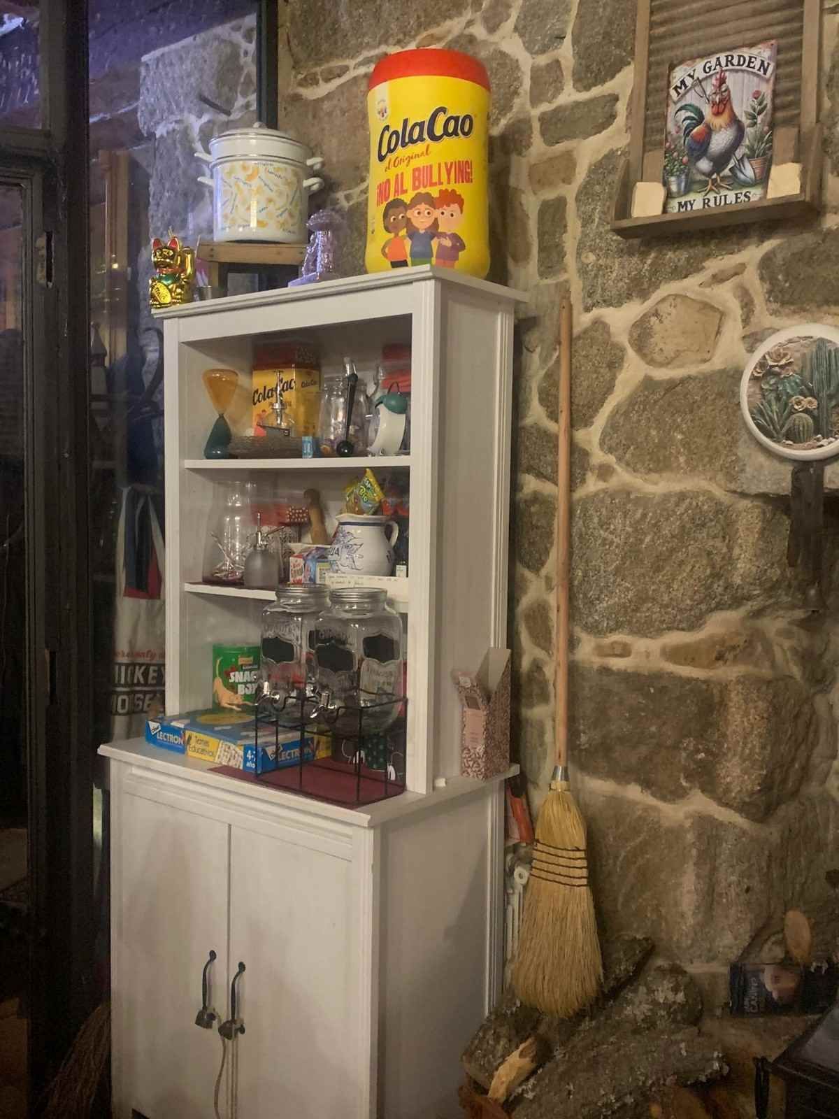 Vitrina de cristal con aperitivos y dulces en un rincón de una tienda rústica de piedra.