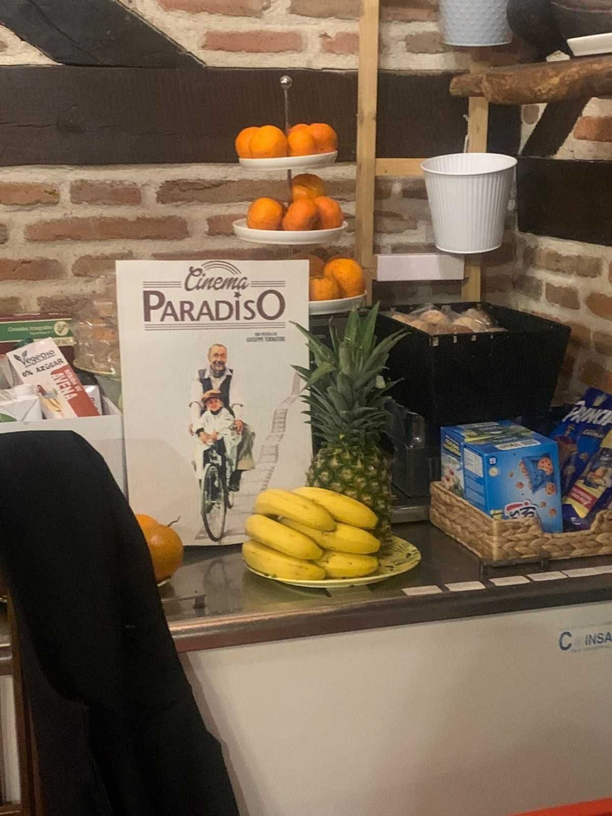 Mostrador con plátanos, naranjas, piña y un letrero que dice