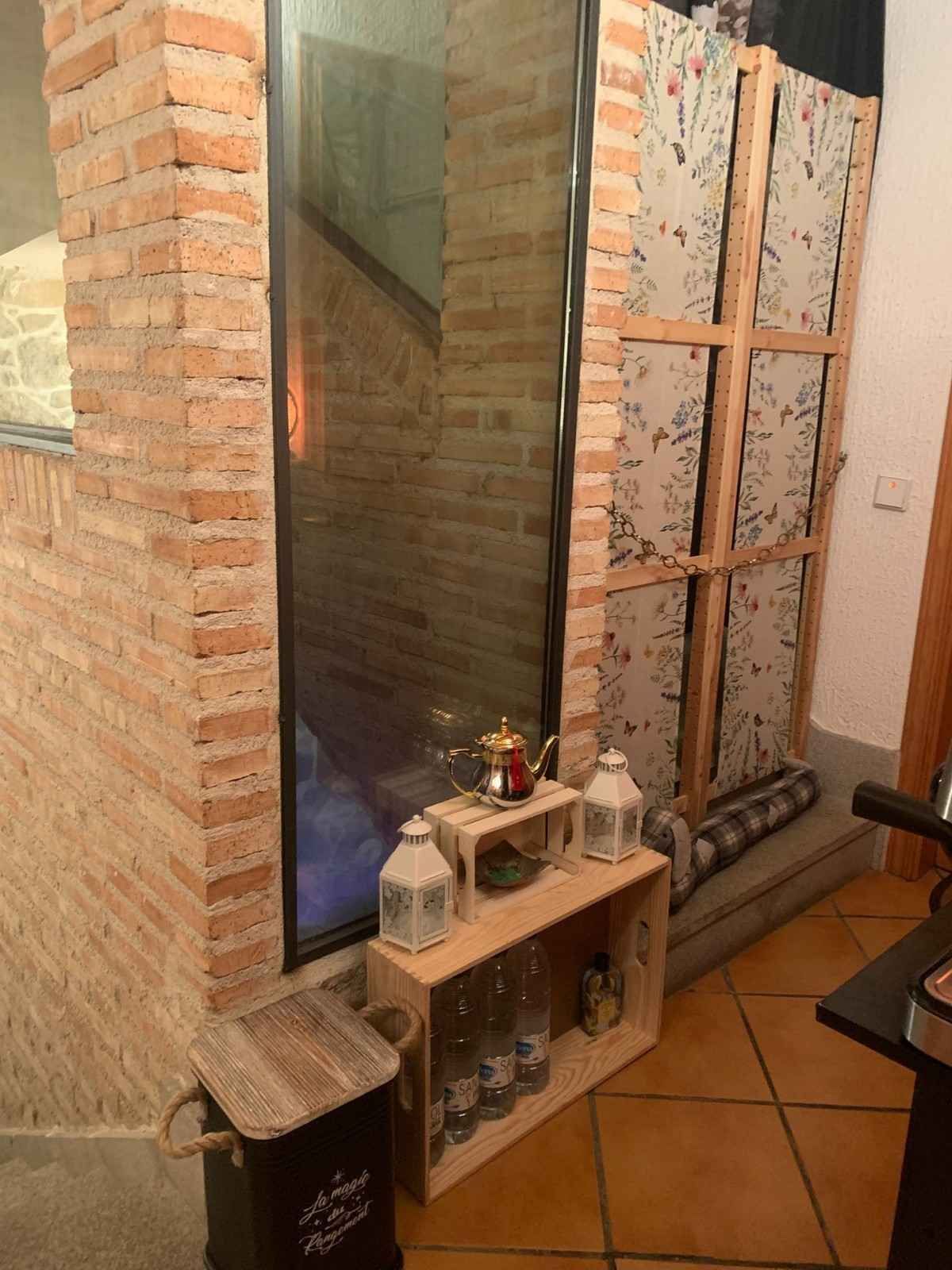 Chimenea de ladrillo con espejo alto, estante pequeño y objetos decorativos en una habitación alicatada.