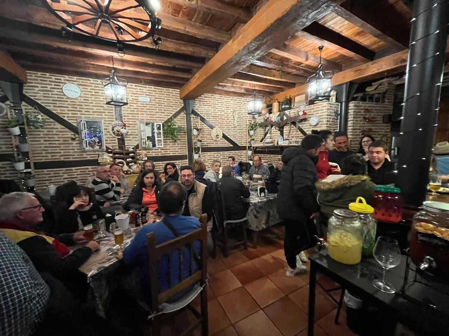 Acogedor restaurante de ladrillo con comensales sentados en mesas de madera y vigas a la vista bajo lámparas colgantes.