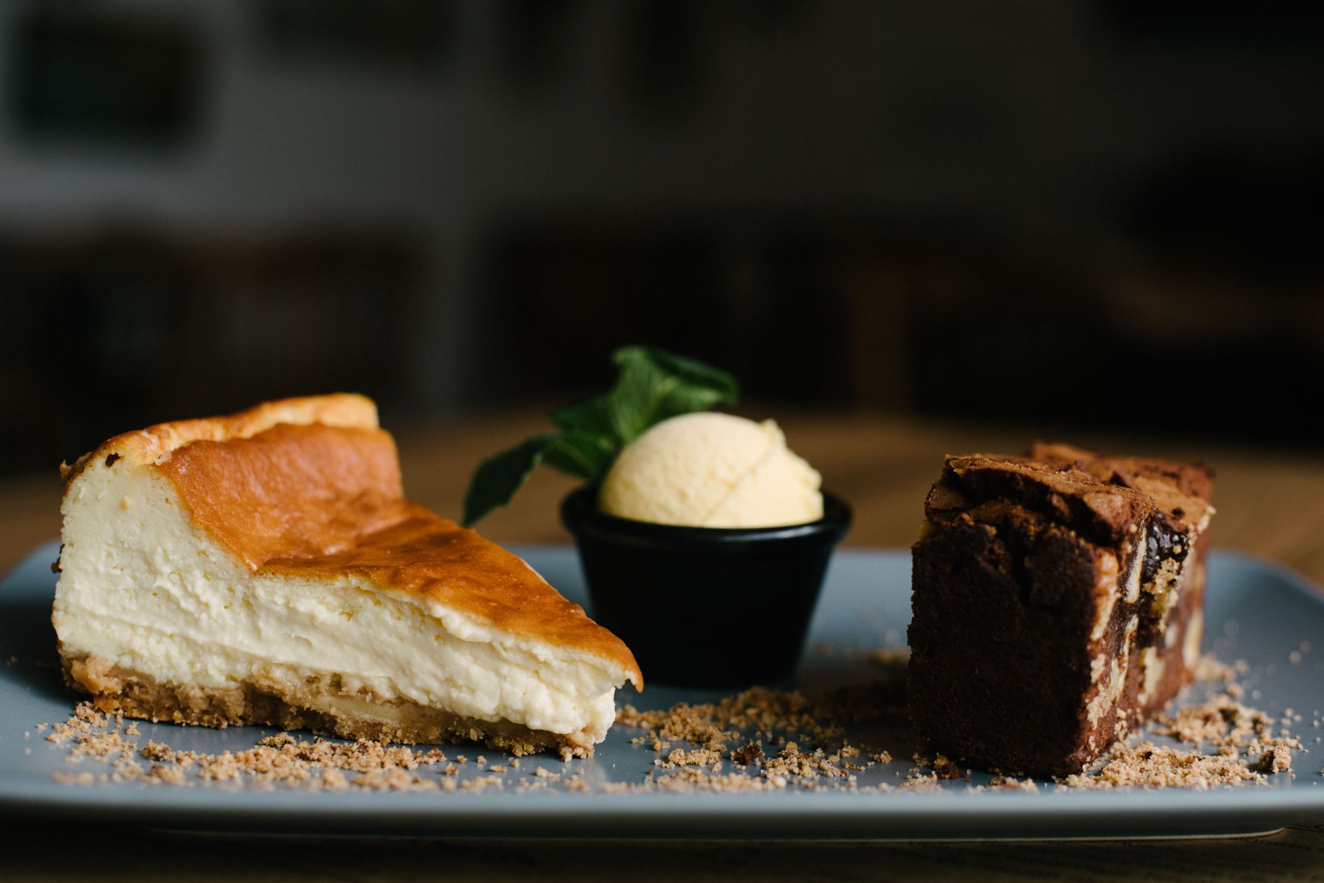 Una rebanada de tarta de queso, un brownie y helado en un plato.