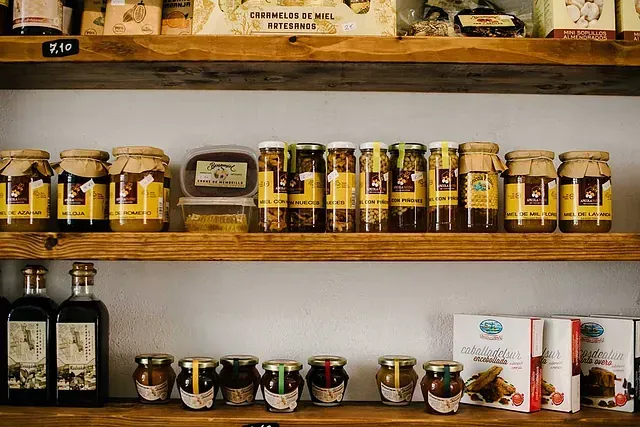 Un estante de madera lleno de frascos y botellas de comida.