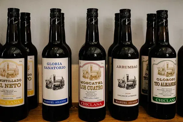 Varias botellas de vino están alineadas en un estante de madera.