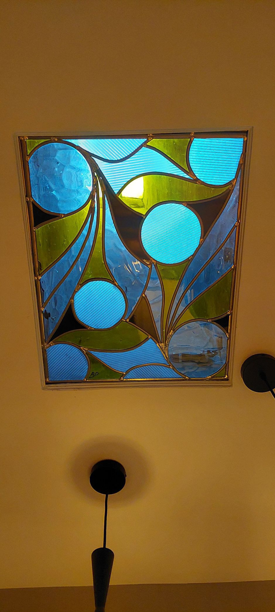 Vitrail avec formes géométriques bleues, vertes…