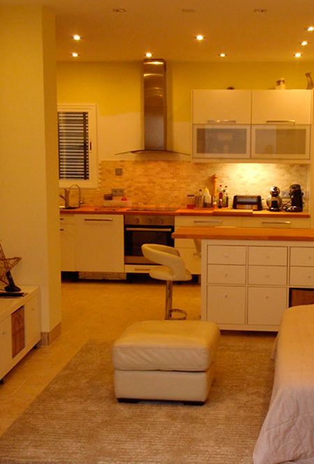 Una cocina con gabinetes blancos y una otomana blanca.