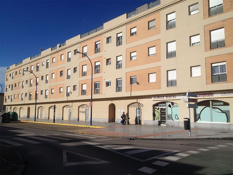 Un gran edificio con muchas ventanas está al lado de una calle.