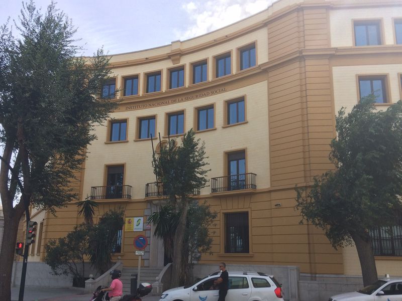 Un coche blanco está aparcado delante de un gran edificio.