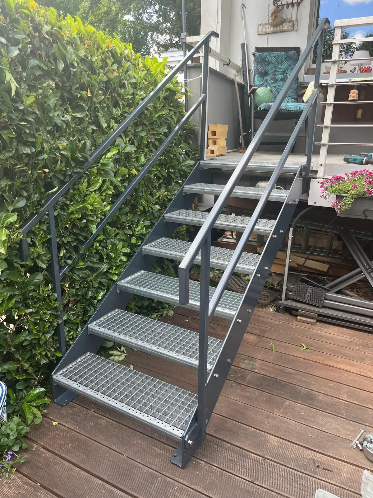 Metallische Außentreppe mit Handläufen, die zu einem Deck führt.