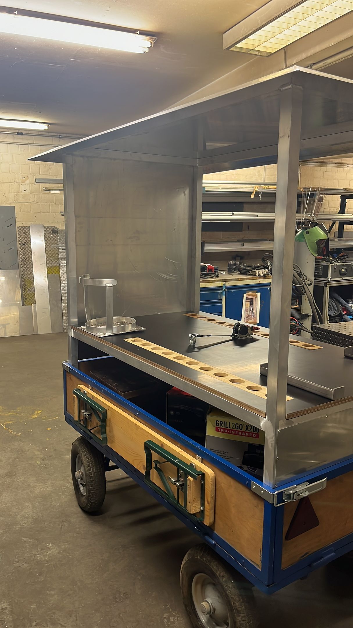 Ein Wagen aus Metall und Holz, möglicherweise ein Imbisswagen in einer Werkstatt.