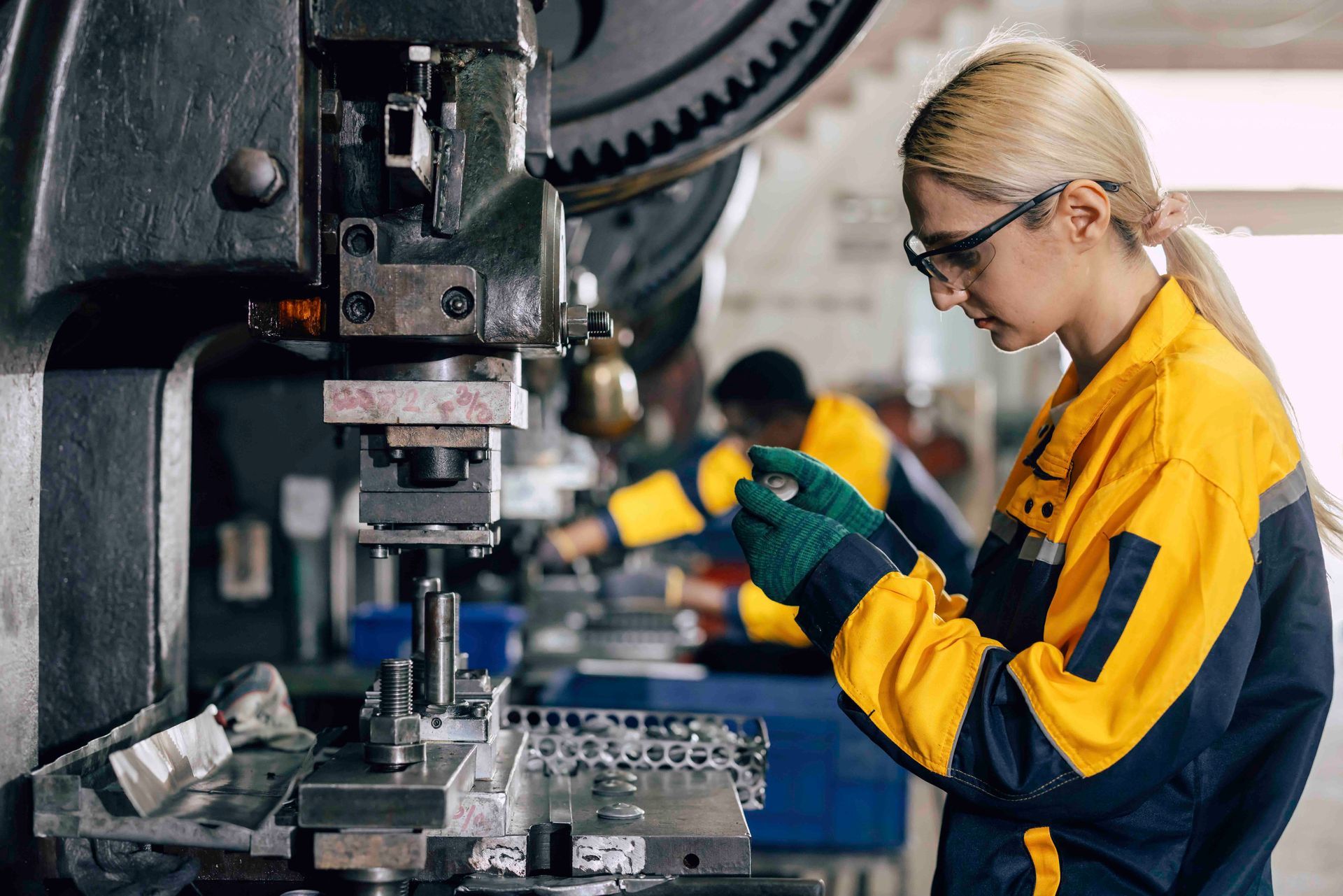 Frau in Sicherheitsausrüstung bedient Industriemaschinen; Fabrikumgebung.
