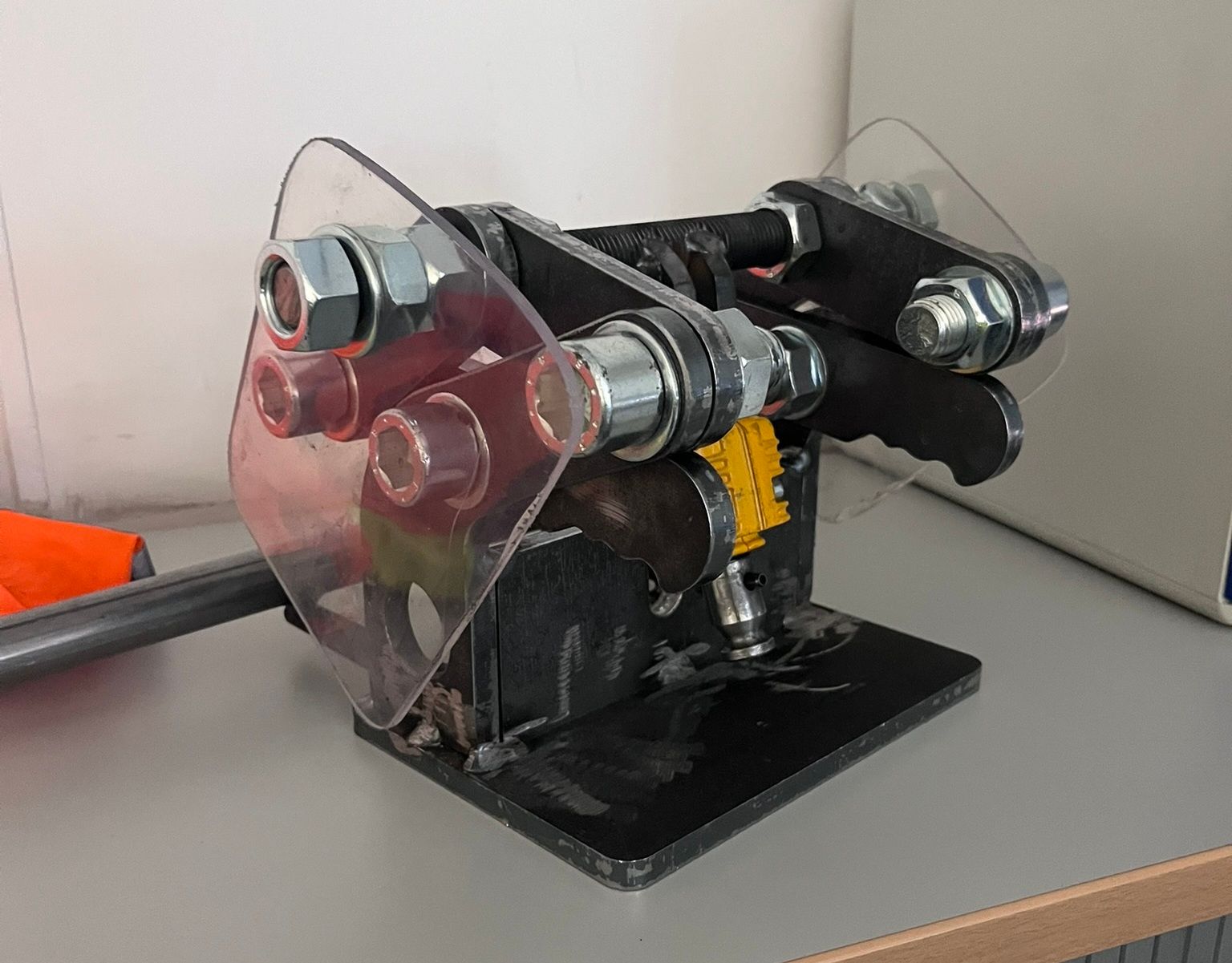 Eine schwarze, selbstgebaute Maschine mit durchsichtigen Kunststoffschutzvorrichtungen und großen Bolzen, möglicherweise zum Biegen von Metall.