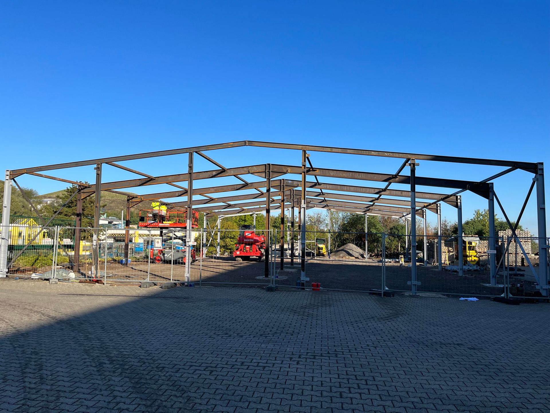 Stahlrahmen eines im Bau befindlichen Gebäudes, auf Kies. Blauer Himmel im Hintergrund.