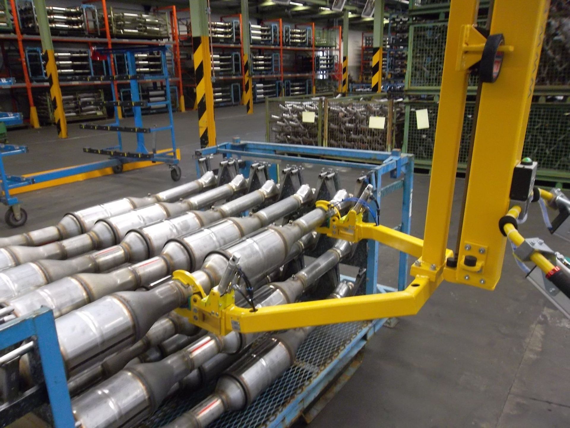 Gelber Roboterarm hebt Autoauspuffrohre in einer Fabrik an.