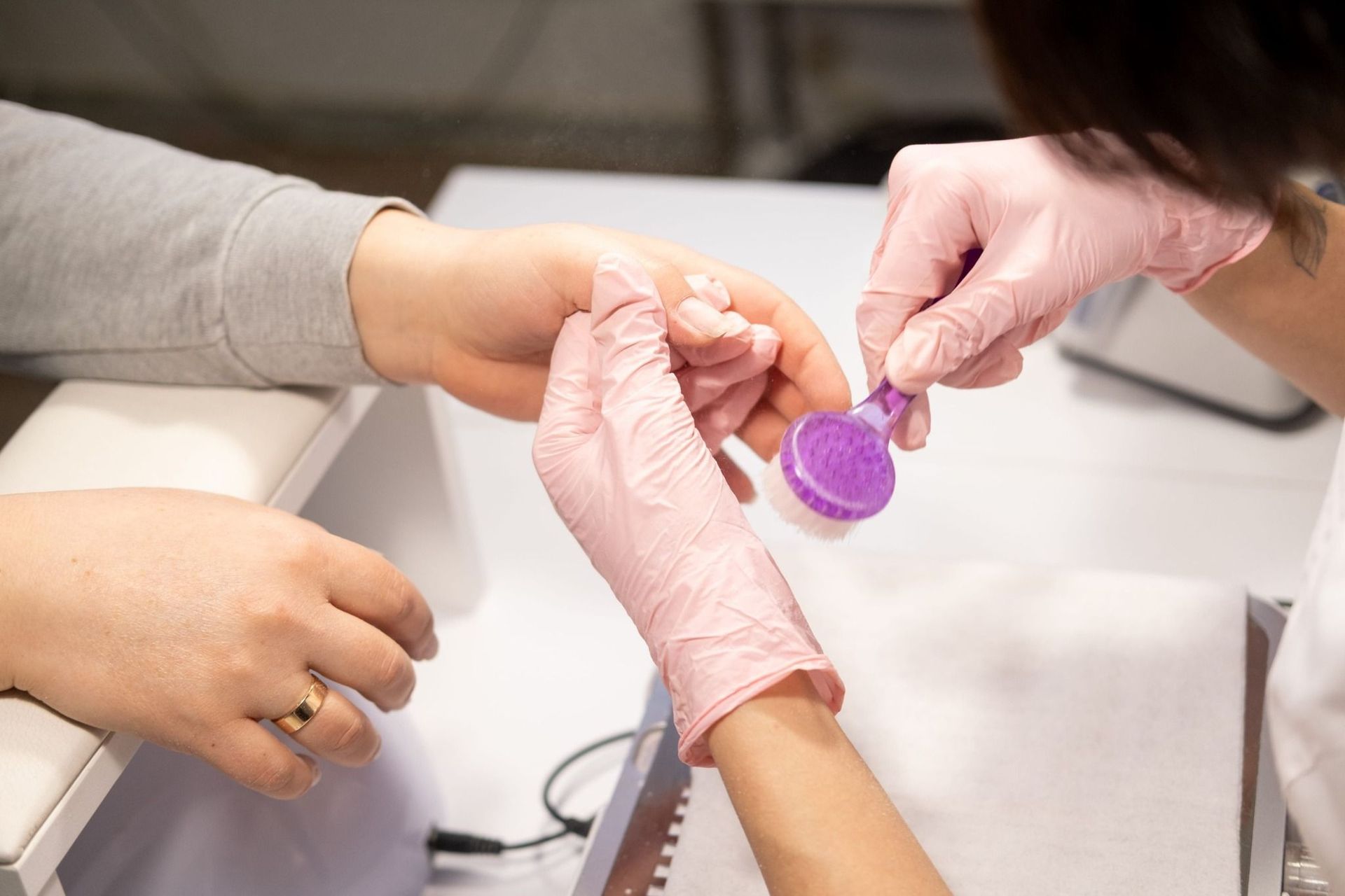Manos enguantadas llenando un pequeño frasco de medicamento morado en el mostrador de una farmacia.