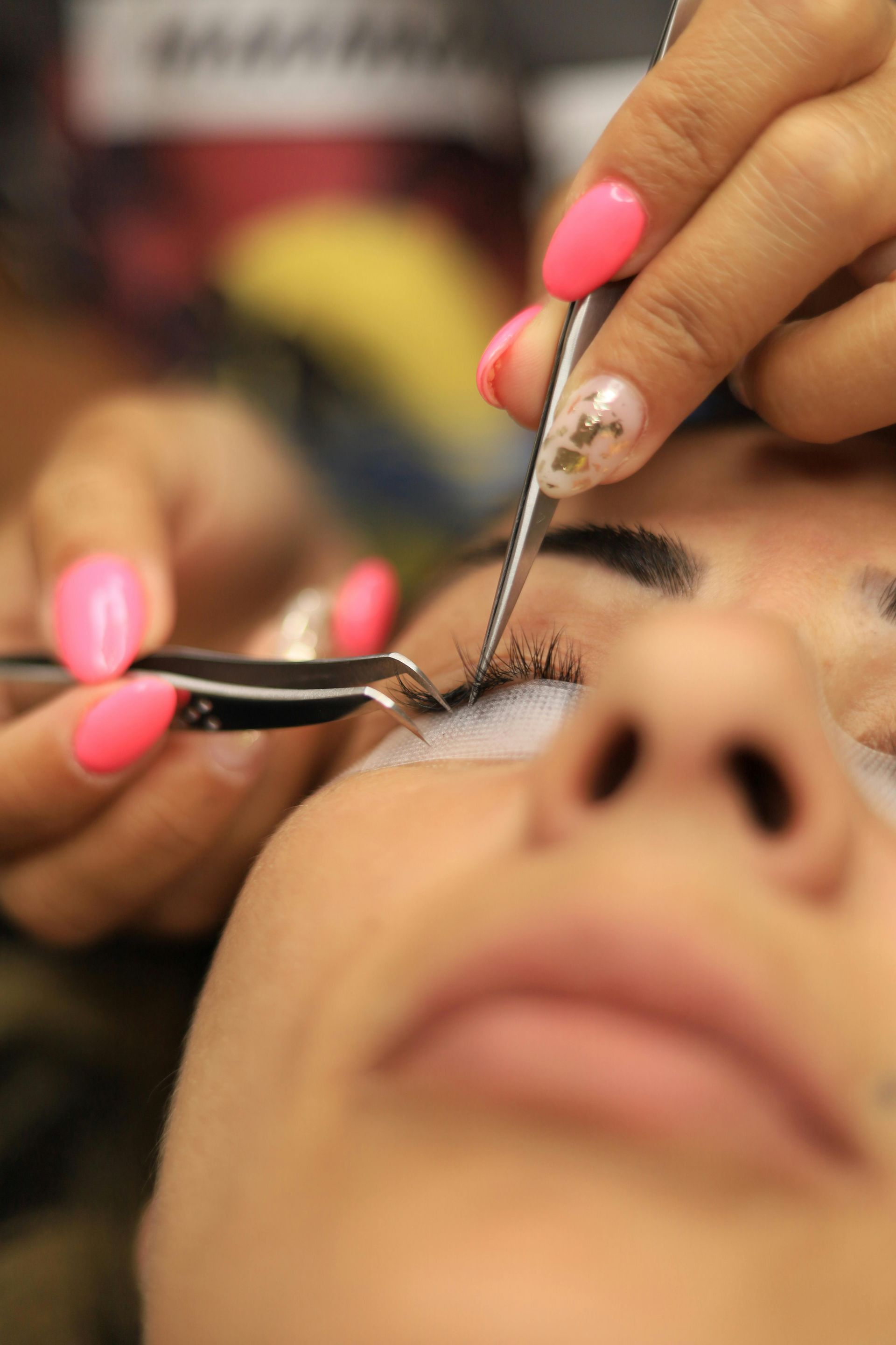 Aplicación de pestañas postizas con pinzas en un primer plano del ojo de una persona.