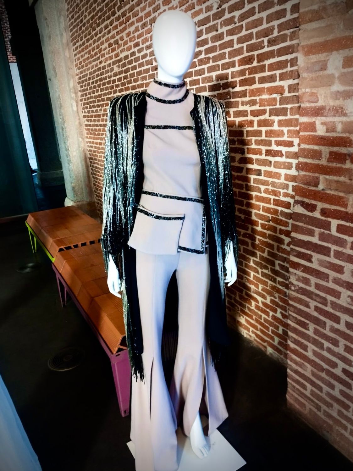 Un maniquí está parado frente a una pared de ladrillos.