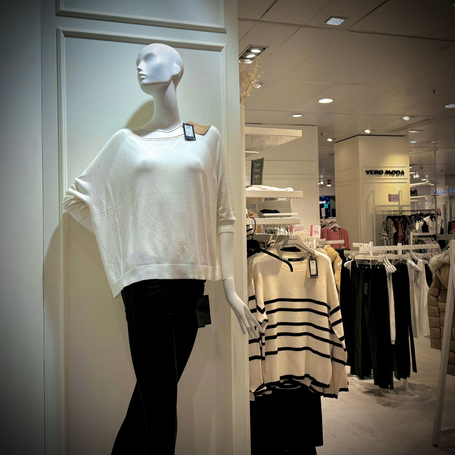 Un maniquí con un suéter blanco en una tienda.