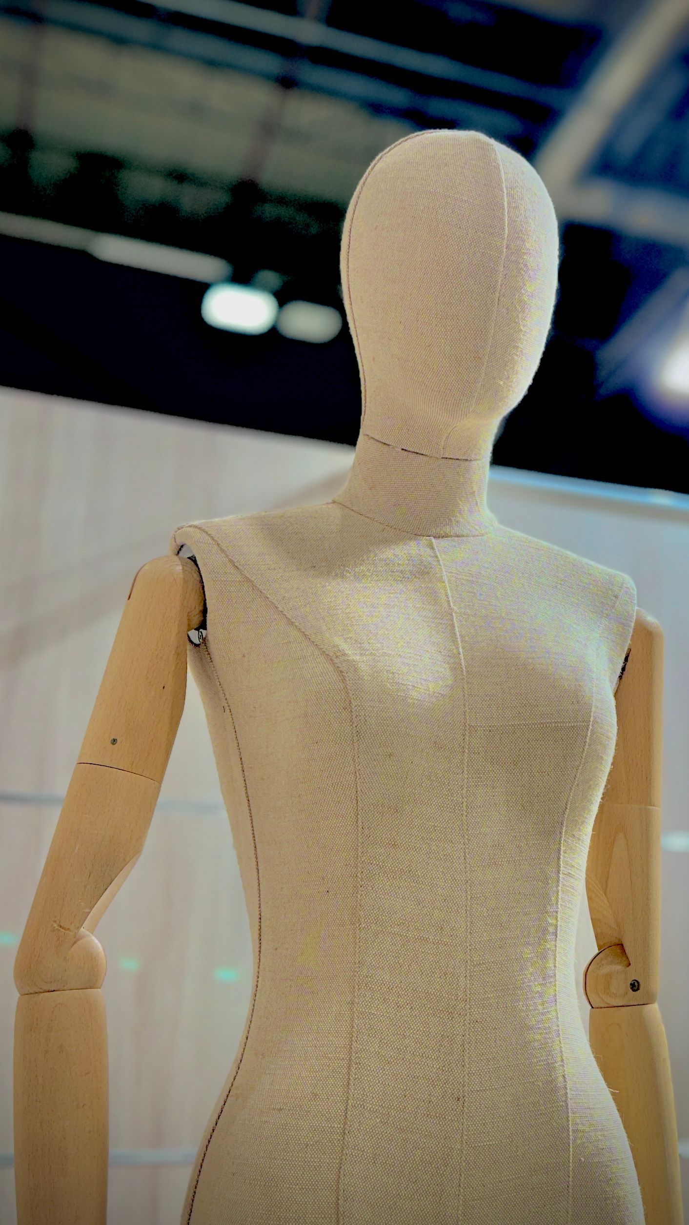 Un maniquí con cabeza blanca y brazos de madera está de pie en una habitación.