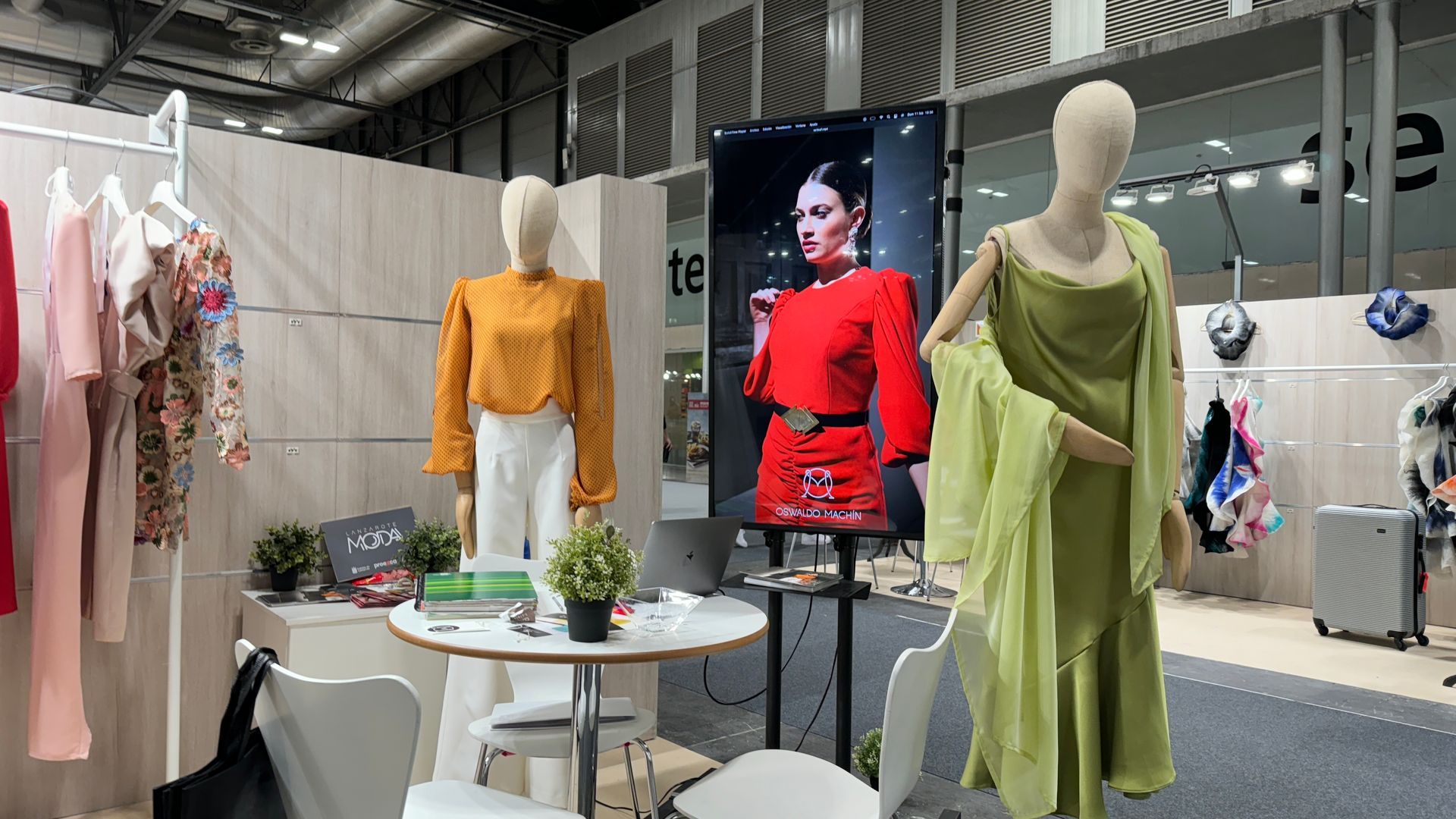 Una mujer con un vestido verde está parada junto a un maniquí en una habitación.