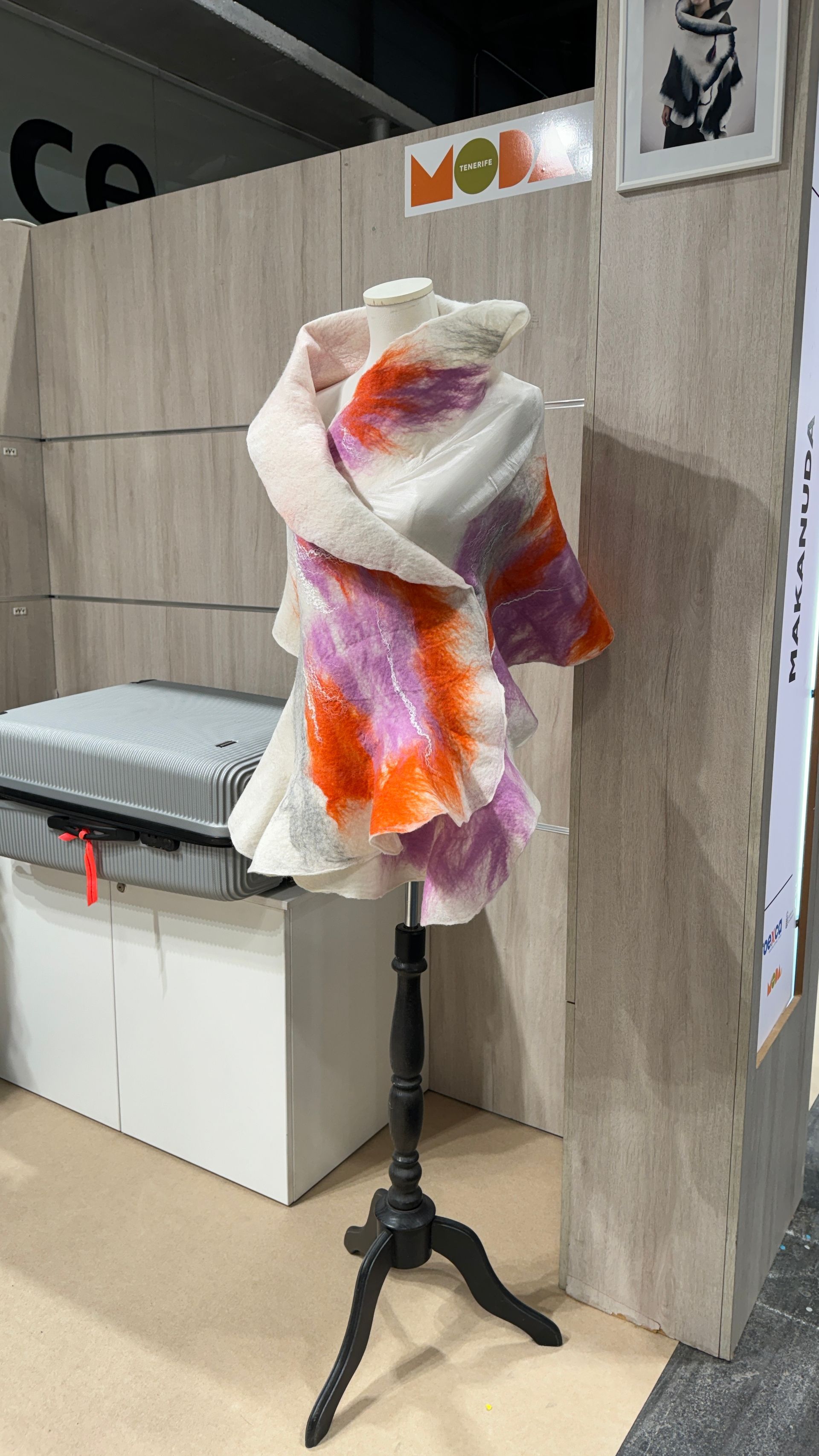 Un maniquí lleva una bufanda colorida en un soporte.