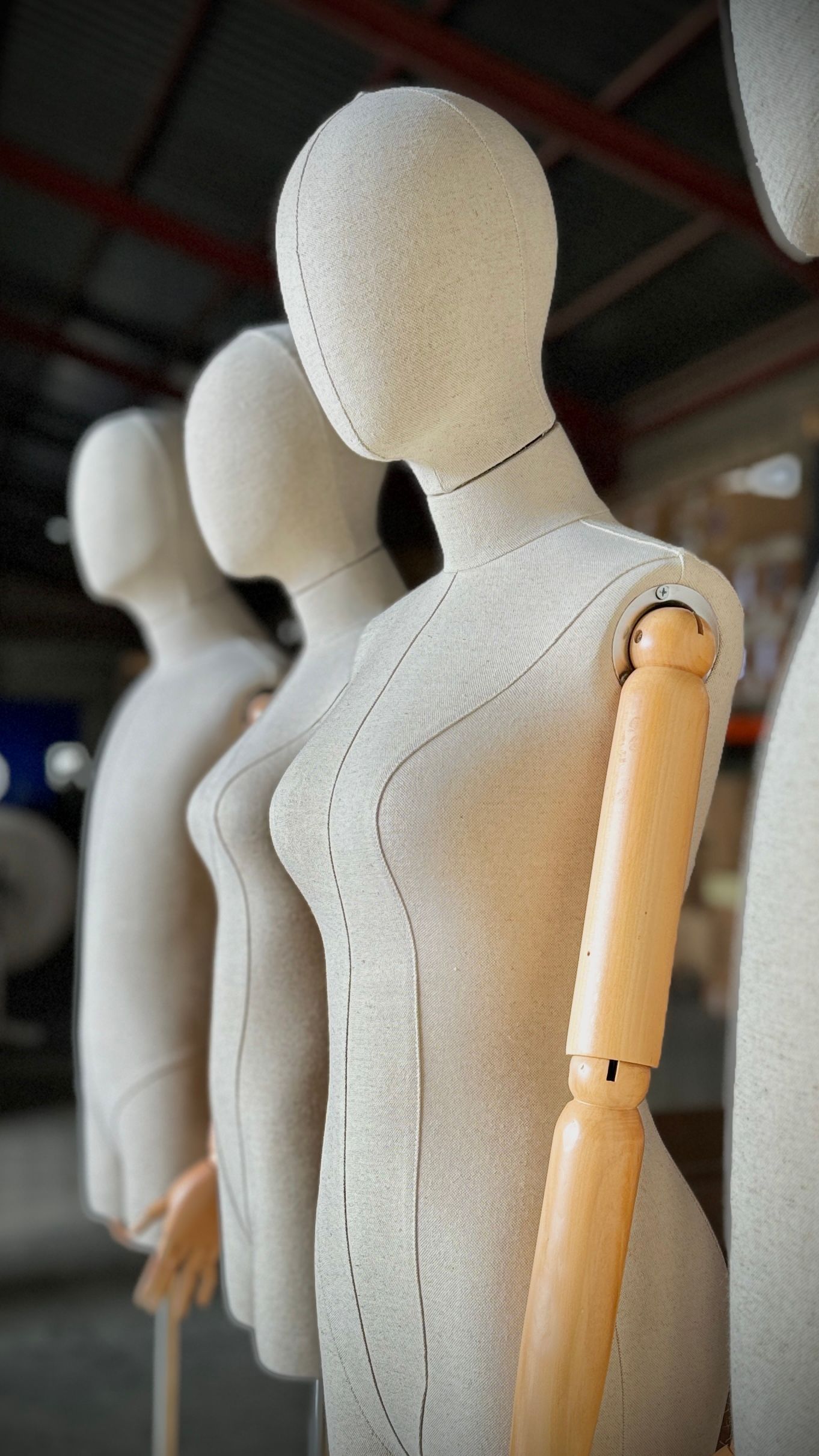 Una fila de maniquíes con brazos de madera están alineados en un almacén.