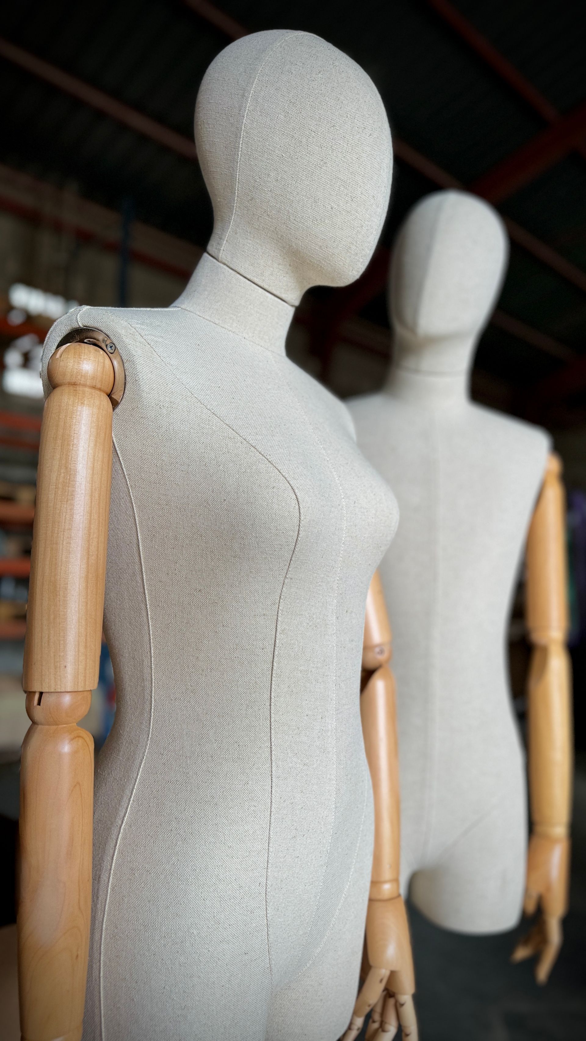 Dos maniquíes con brazos de madera están parados uno al lado del otro en un almacén.