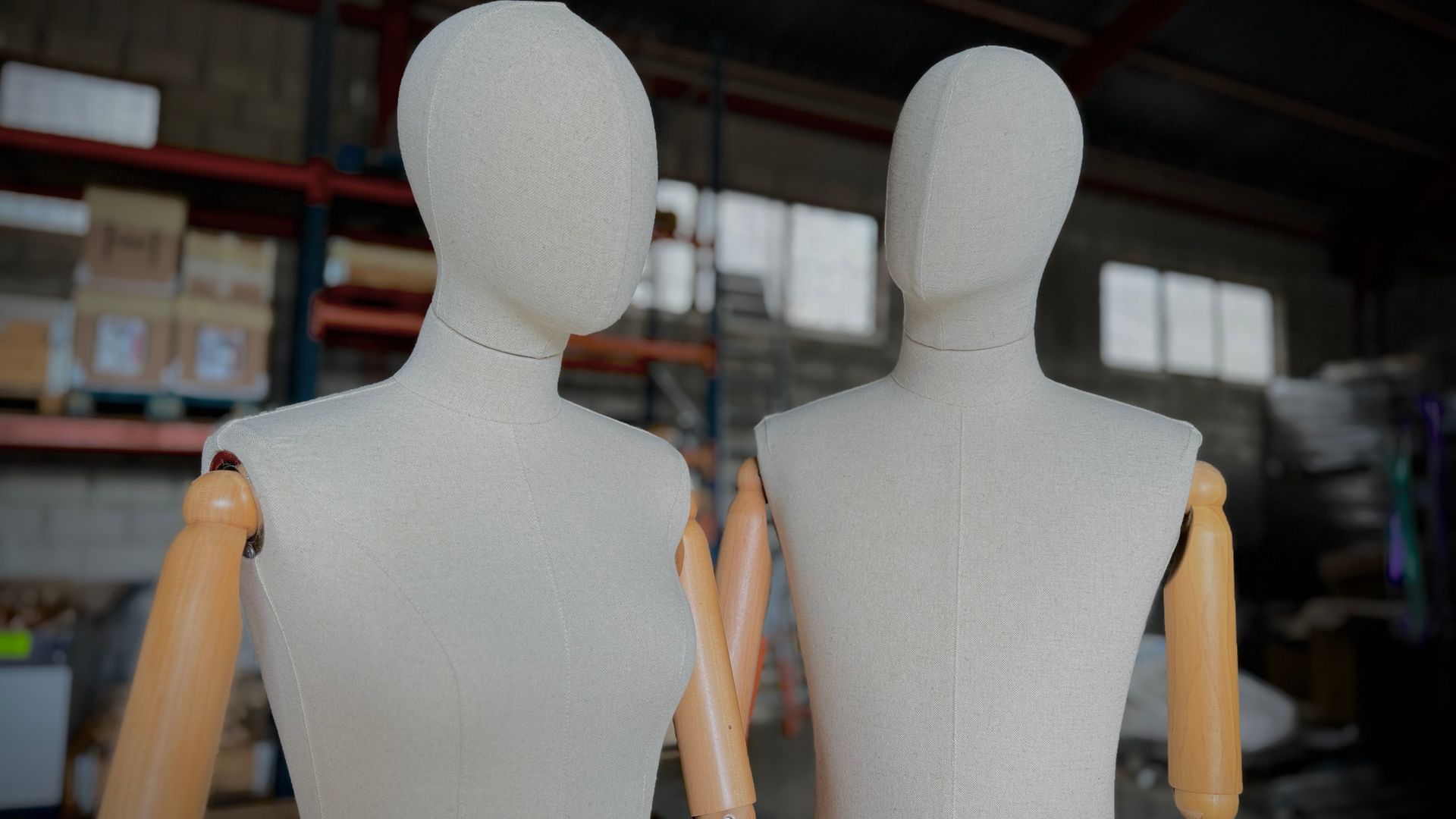 Dos maniquíes con brazos de madera están uno al lado del otro en un almacén.