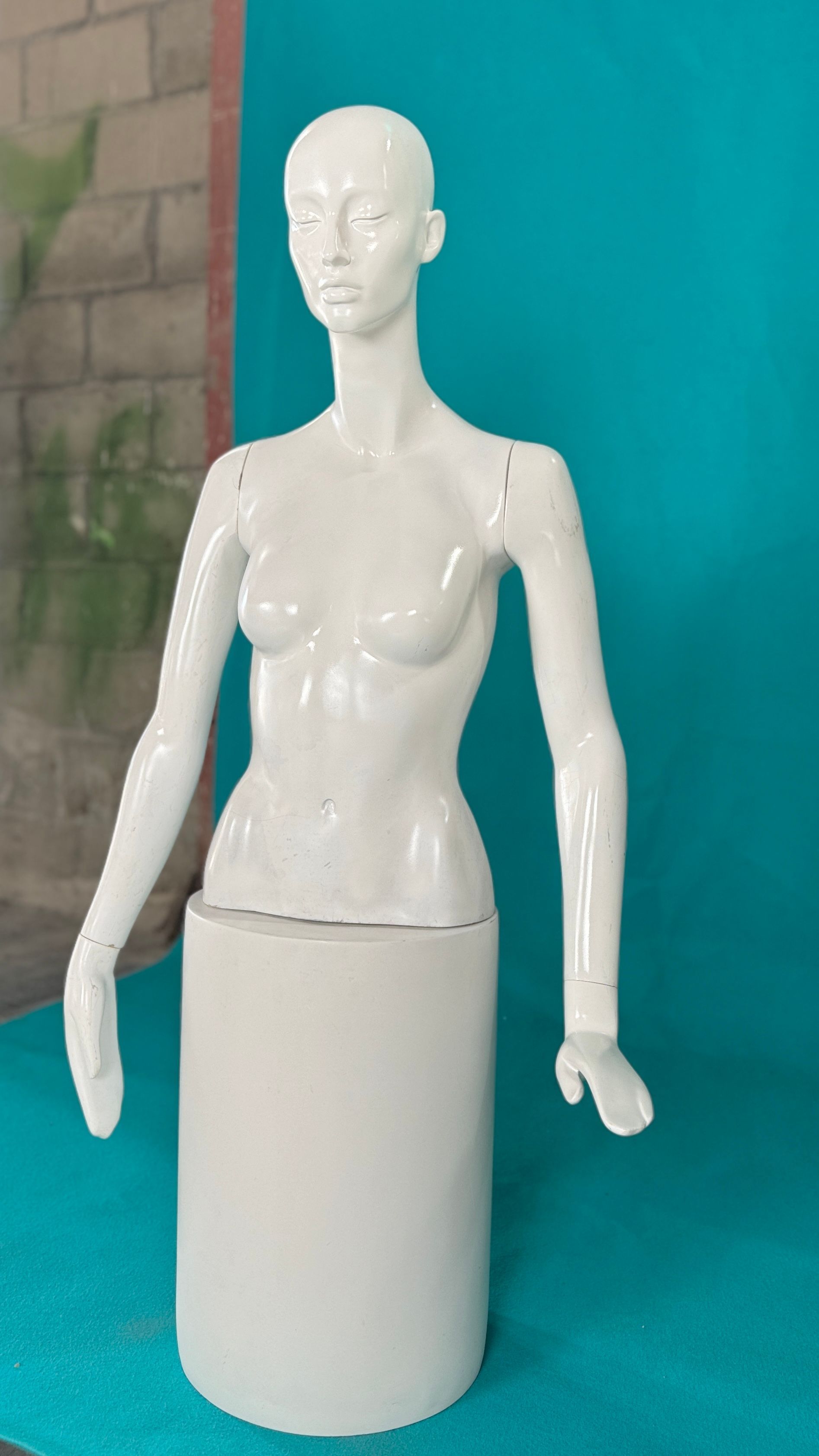 Un maniquí blanco está sentado sobre una superficie azul.