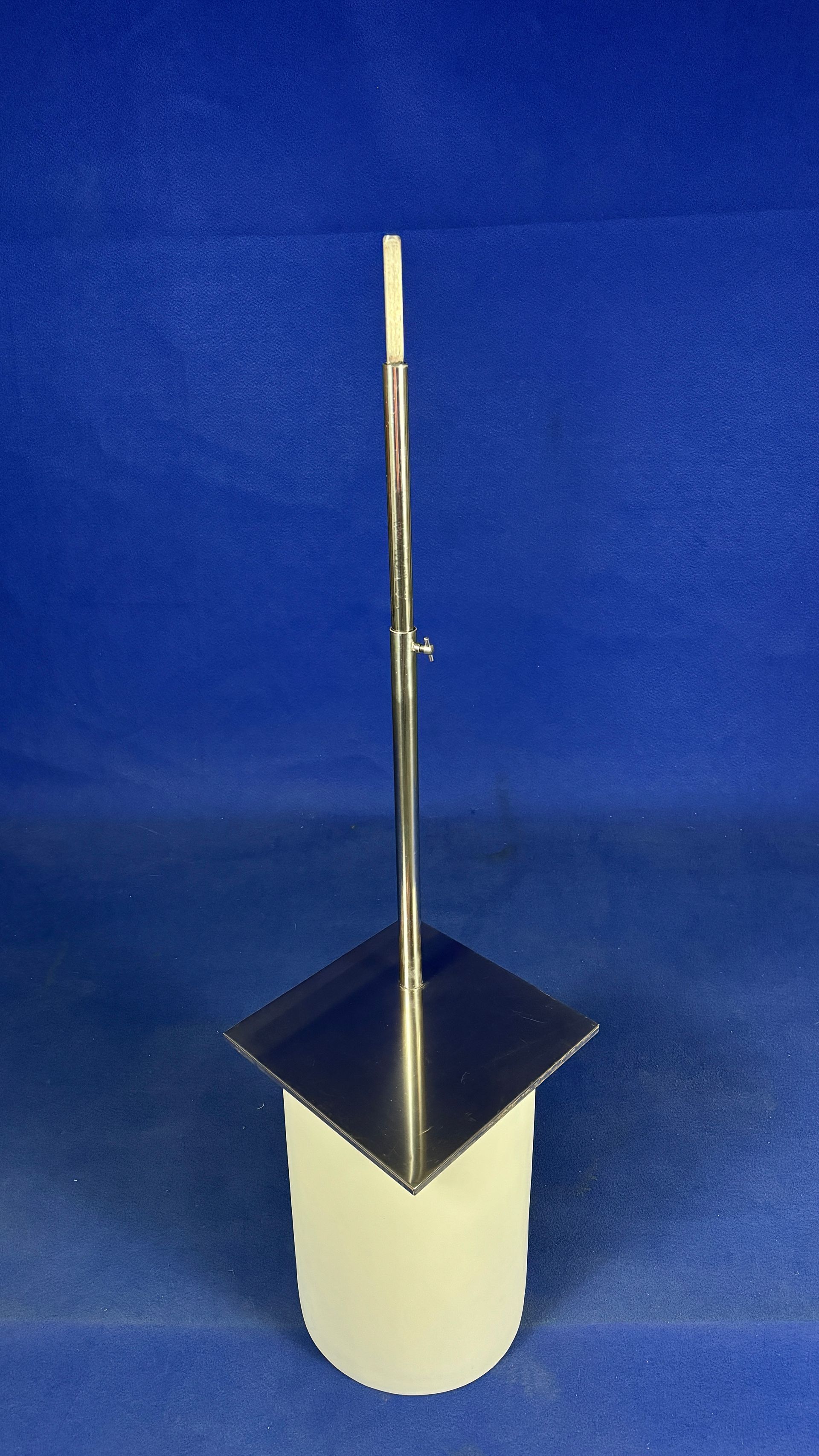 Un poste de metal reposa sobre un cilindro blanco sobre una superficie azul.