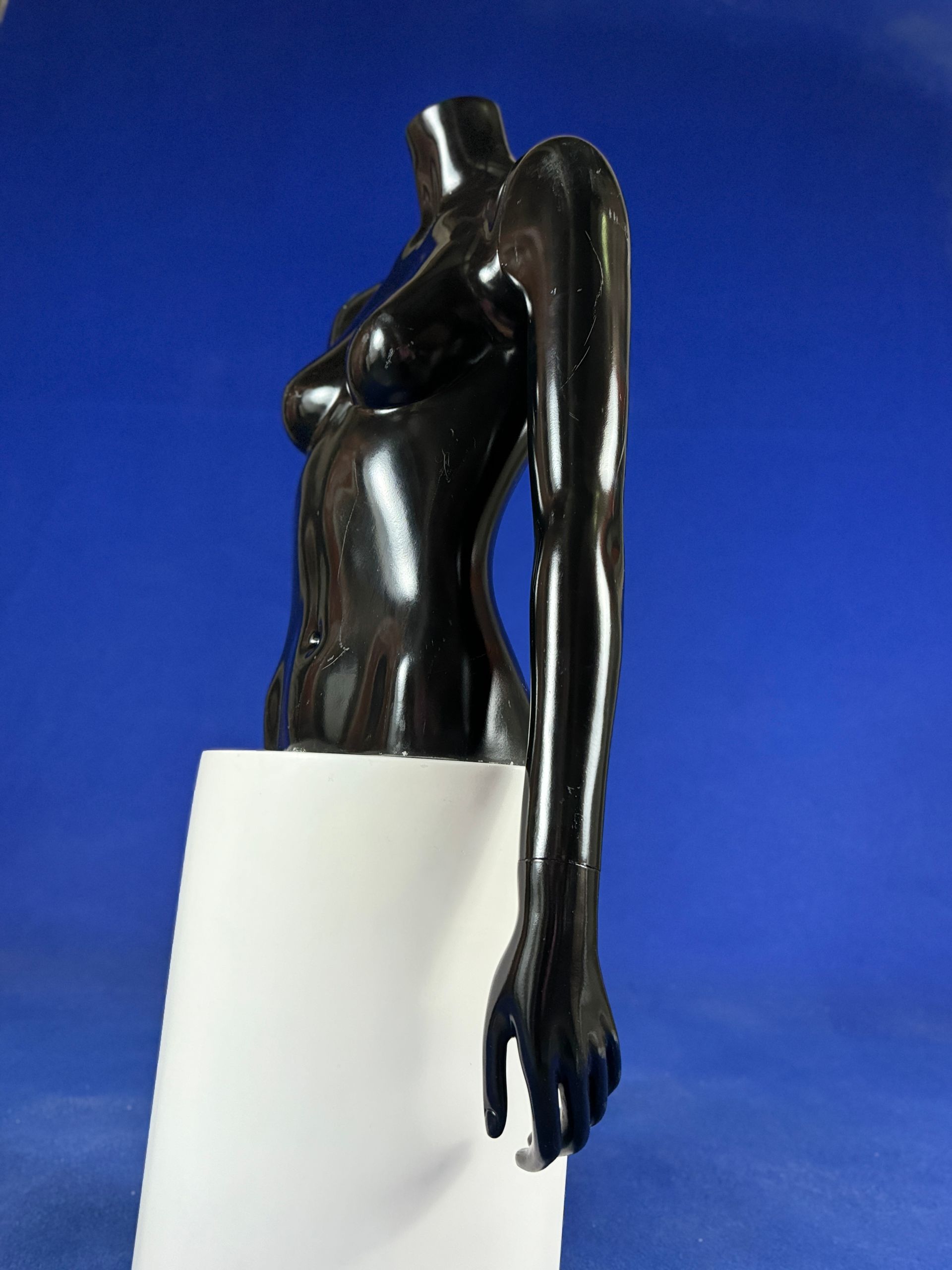 Una estatua del brazo de una mujer está sobre un pedestal blanco.