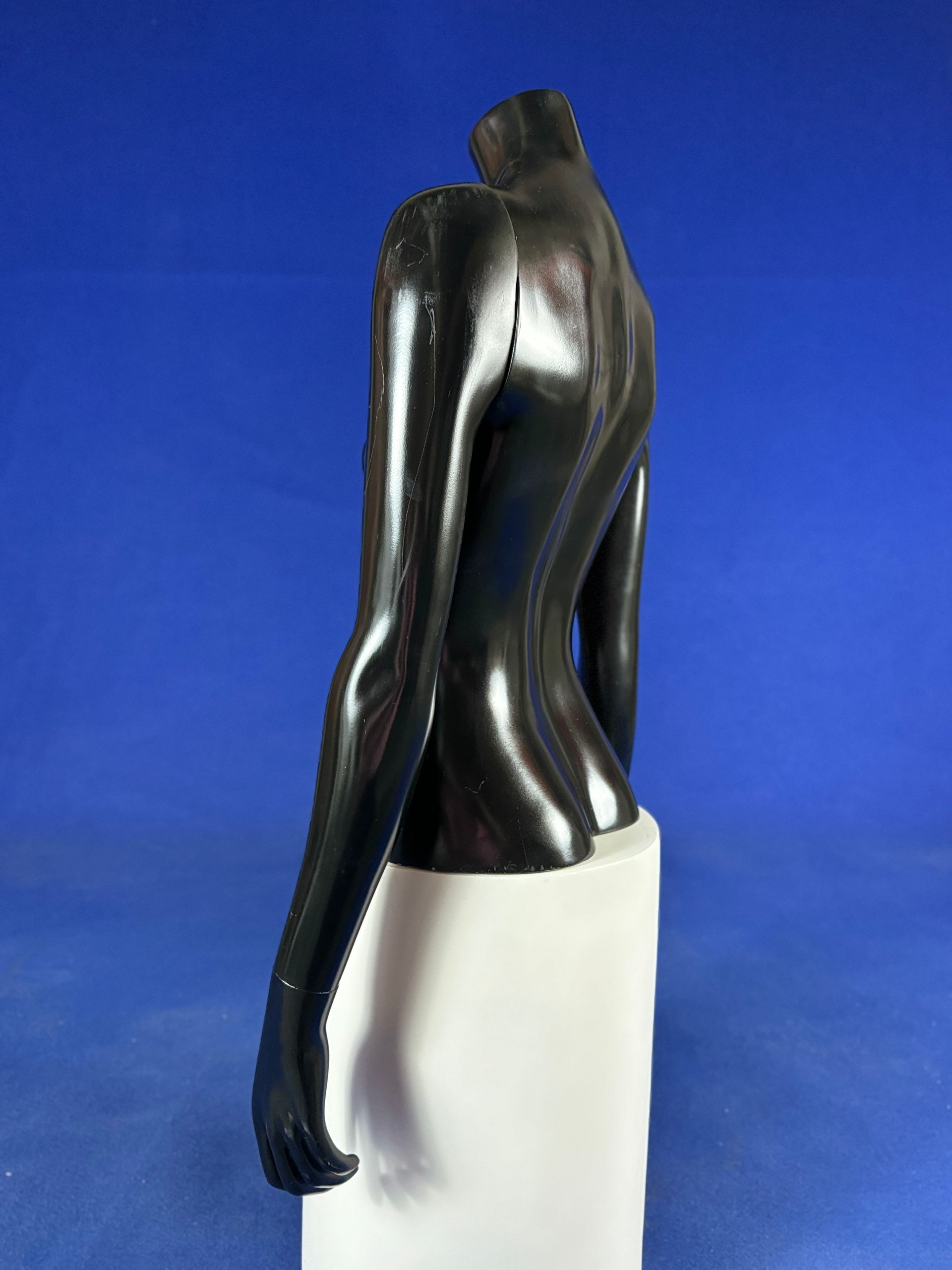 Una estatua de una mujer sin cabeza está sentada sobre un bloque blanco.