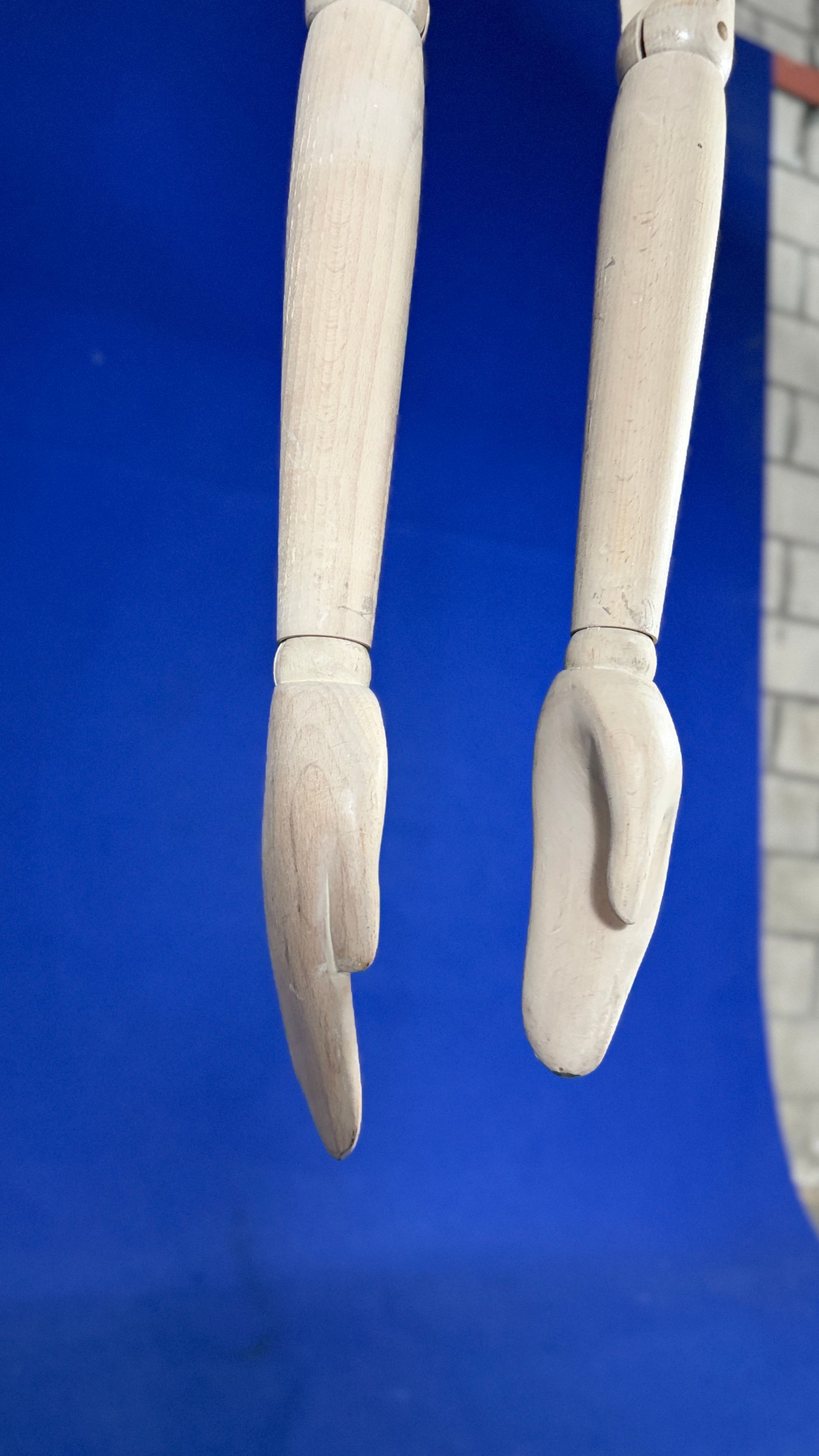 Un par de brazos blancos colgando de una pared azul.