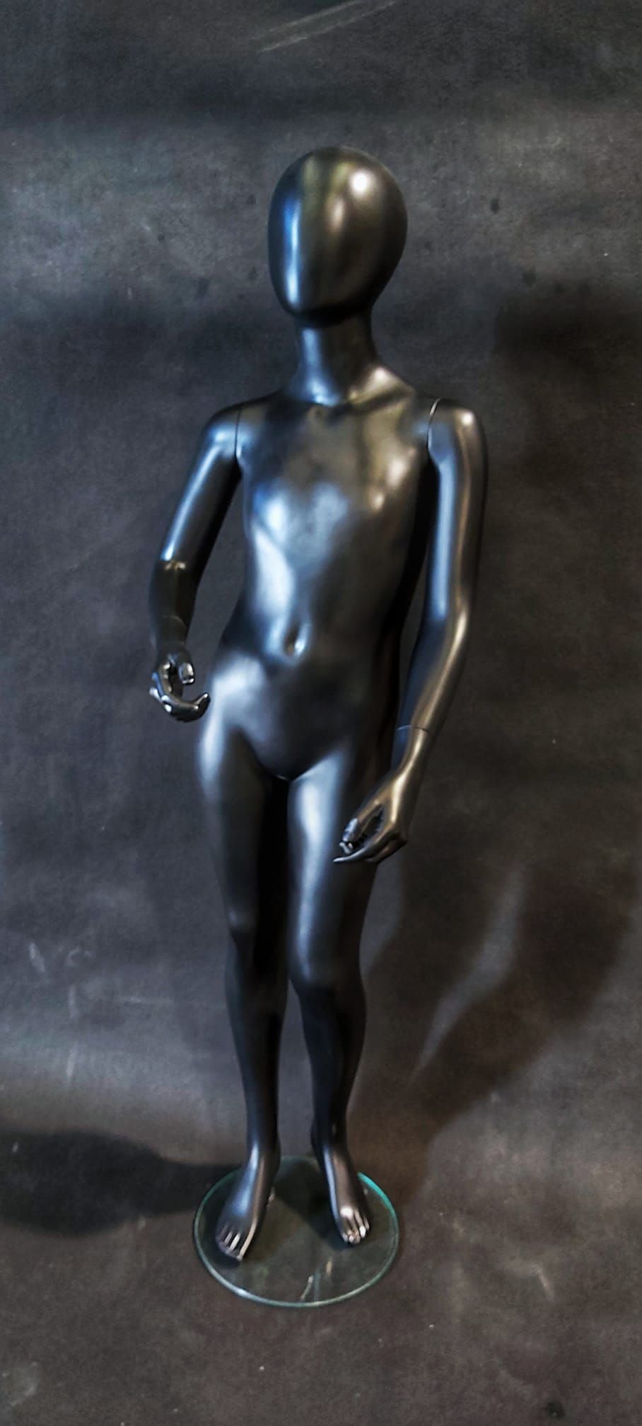 Un maniquí negro está de pie sobre una superficie negra.