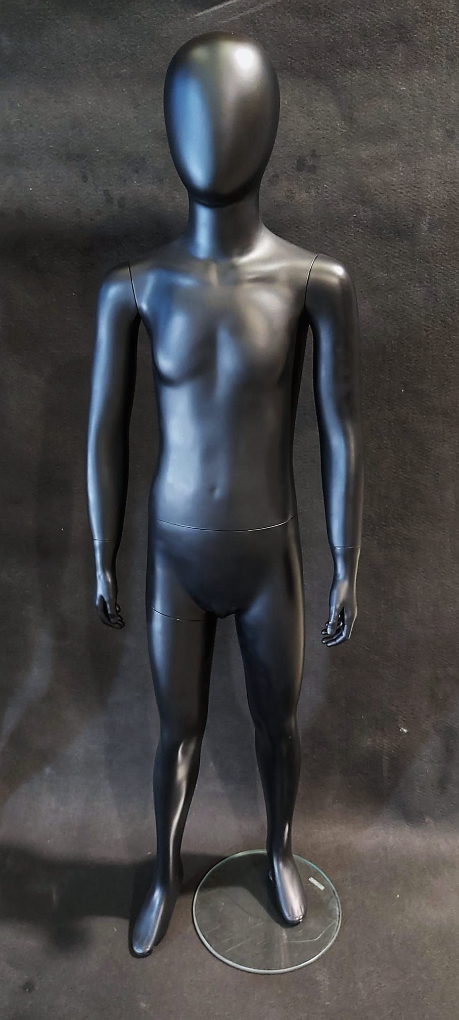 Un maniquí negro está de pie sobre una superficie negra.