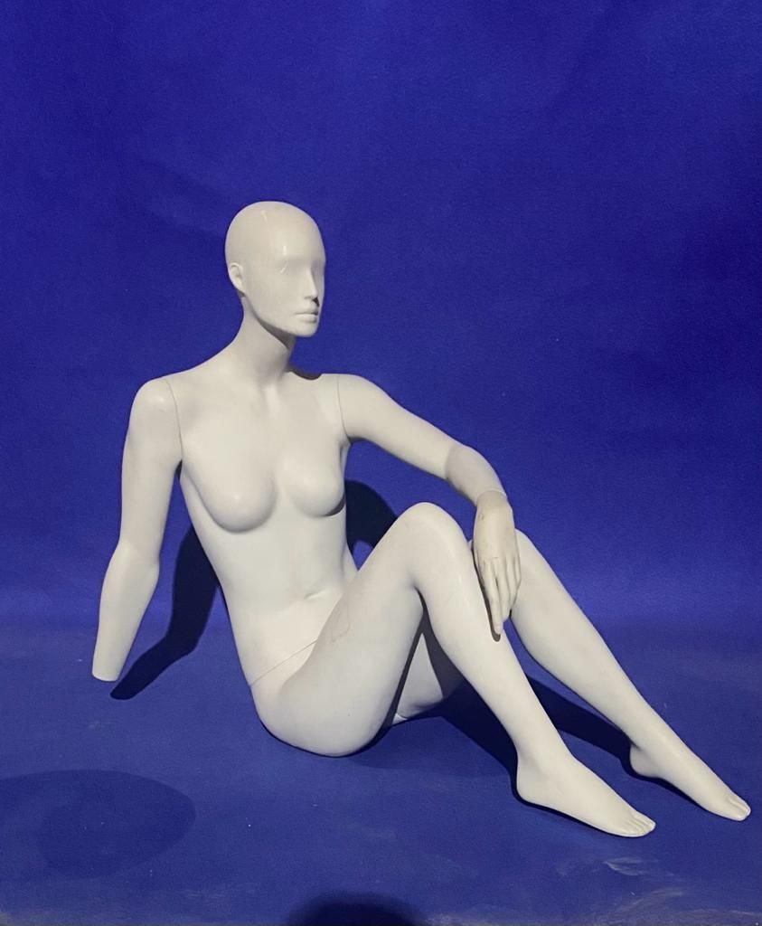 Un maniquí blanco está sentado sobre una superficie azul.