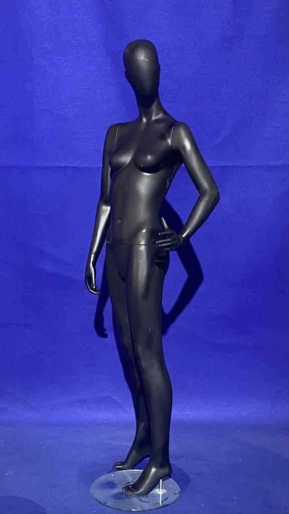 Un maniquí femenino negro está de pie sobre un fondo azul.