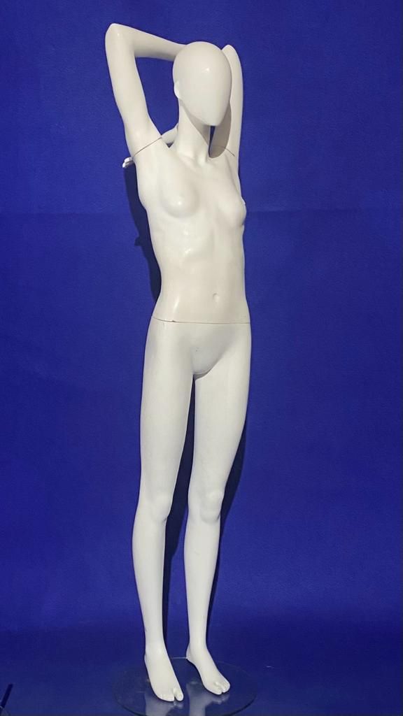 Un maniquí blanco está de pie con las manos detrás de la cabeza sobre un fondo azul.