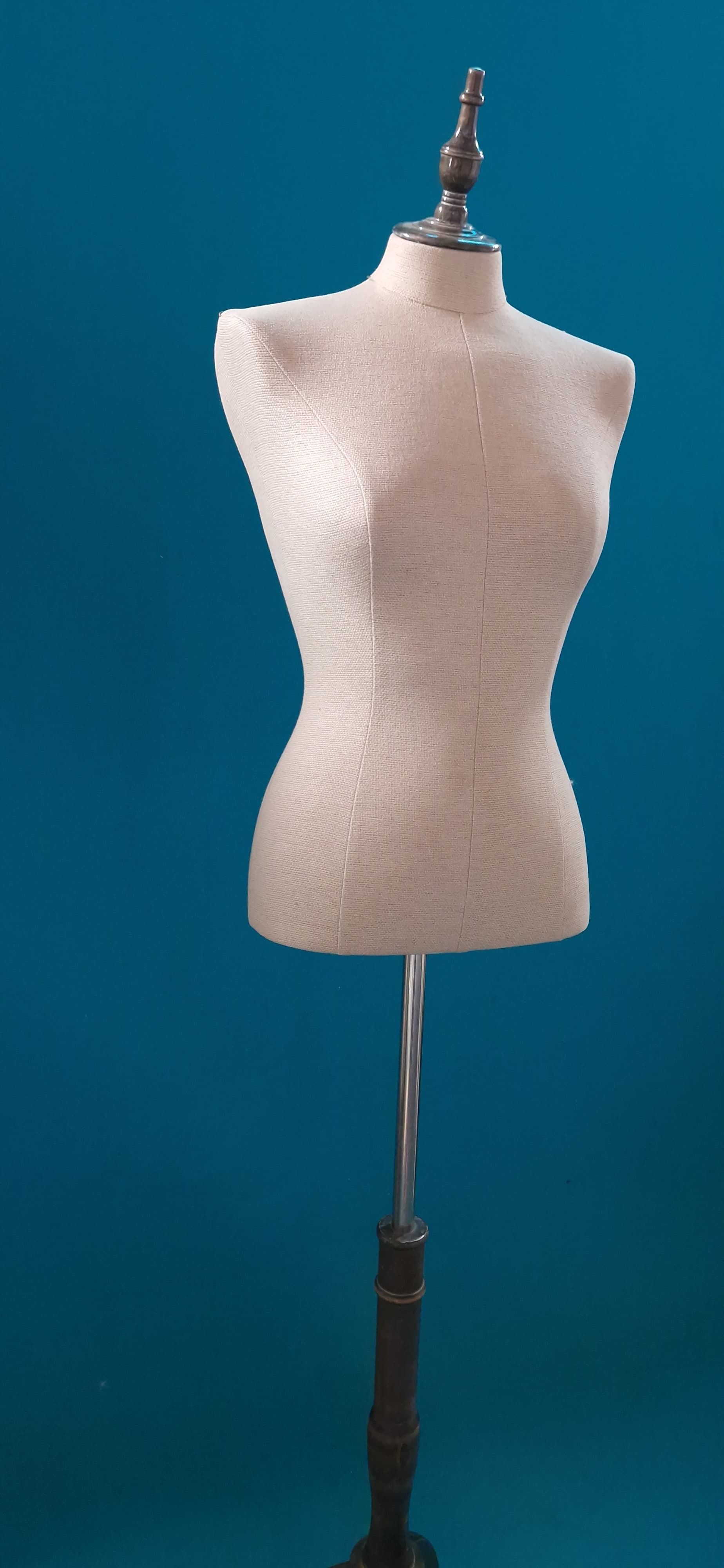 Un maniquí blanco está parado frente a una pared azul.