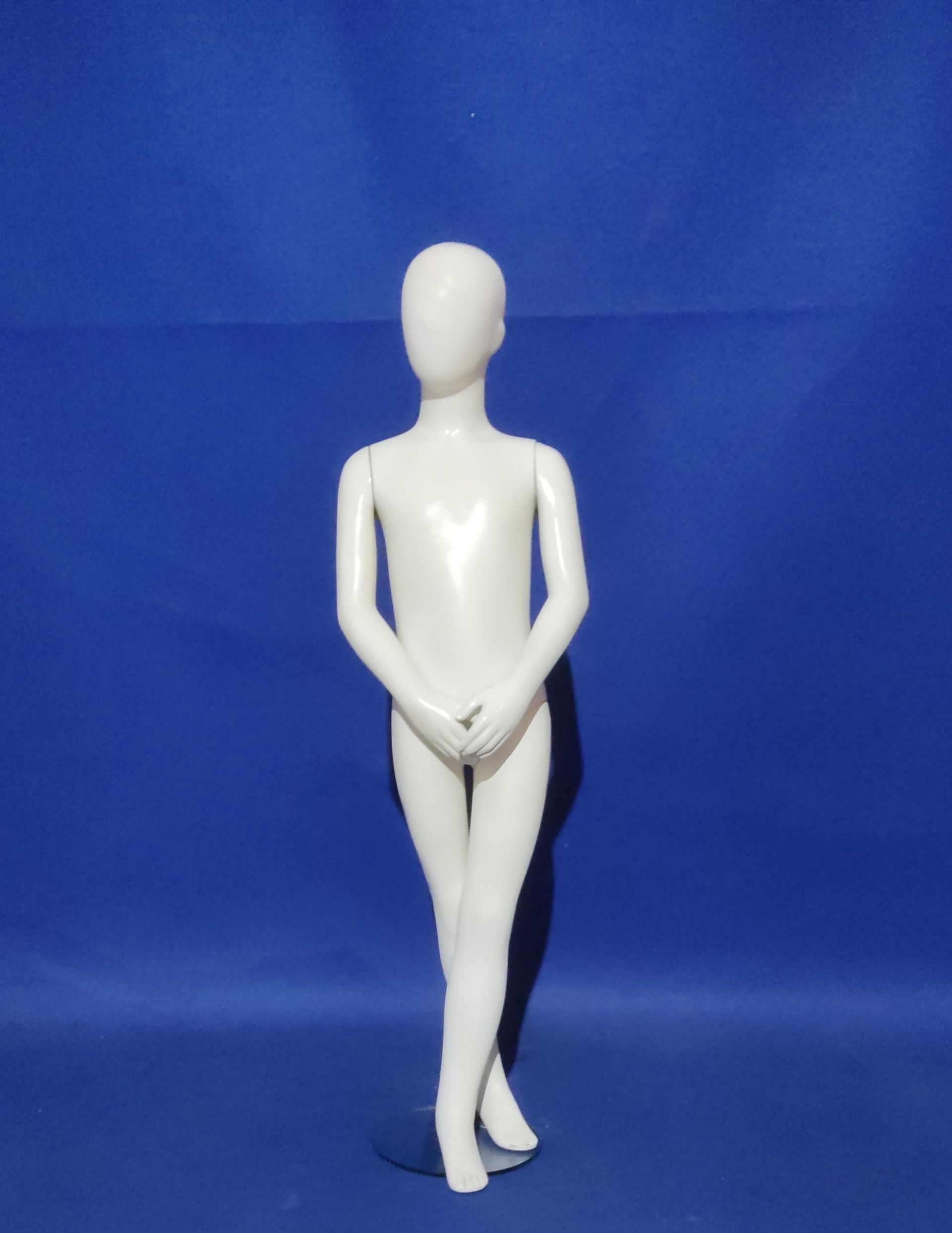 Un maniquí blanco está parado frente a un fondo azul.