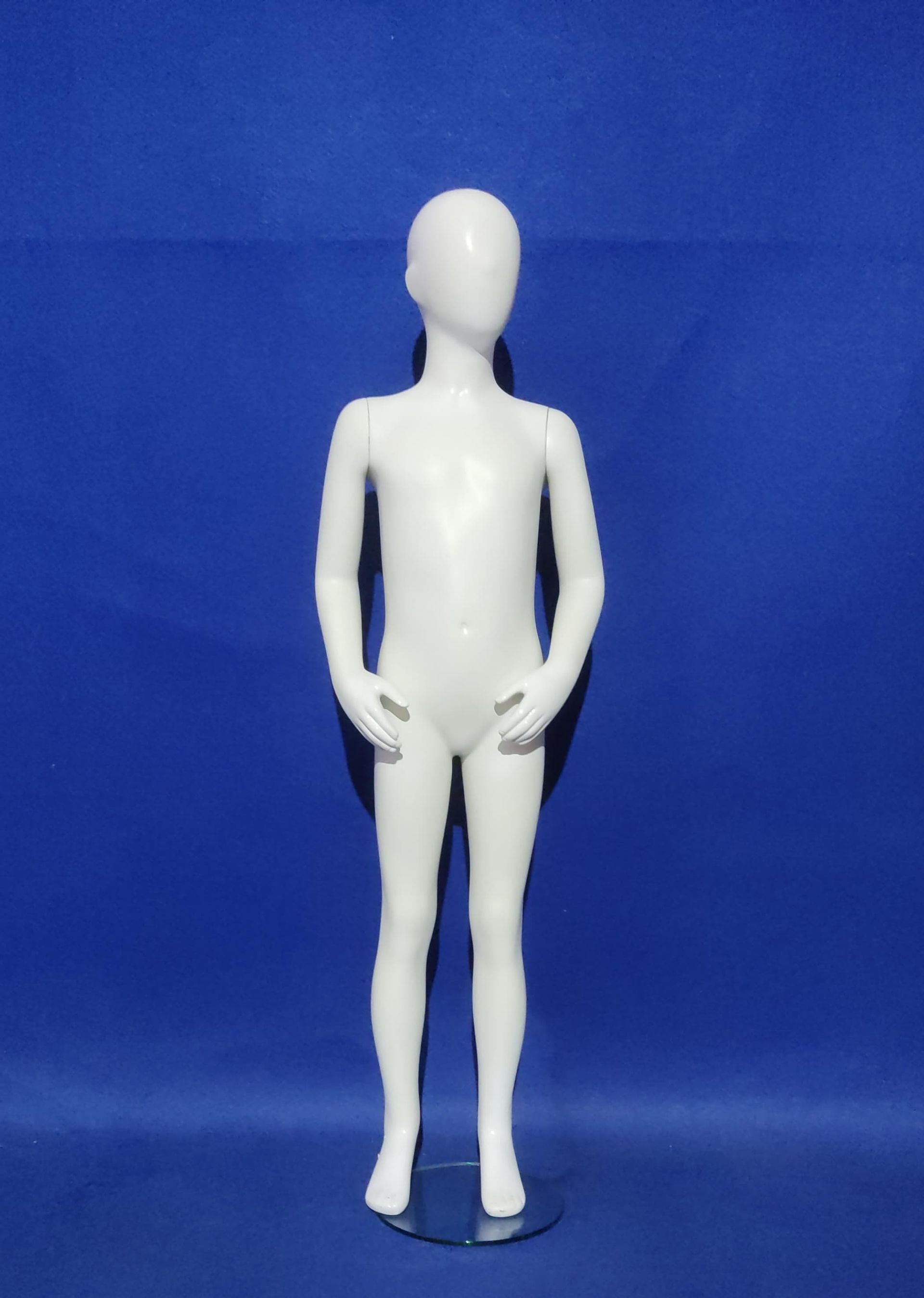 Un maniquí de niño blanco está de pie sobre un fondo azul.