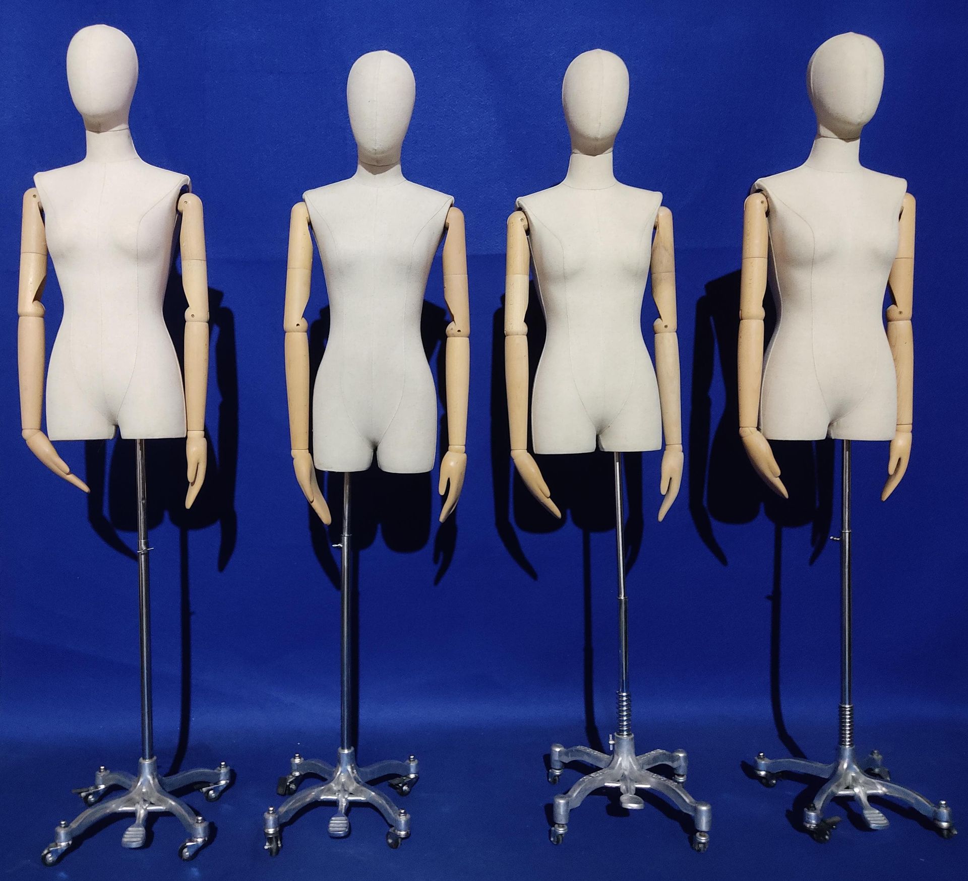 Cuatro maniquíes con brazos de madera están alineados en fila.