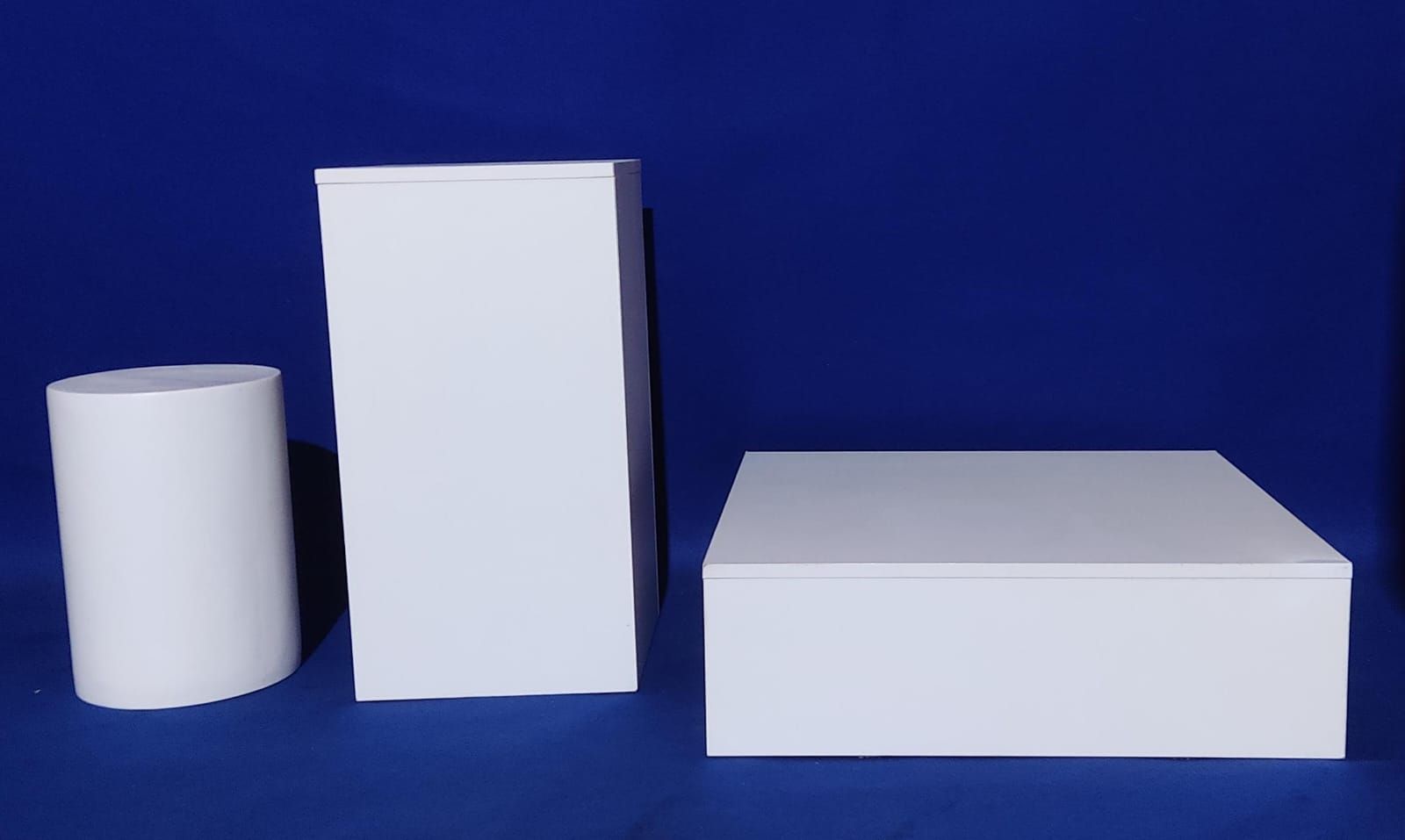 Tres cajas blancas están sobre una superficie azul.