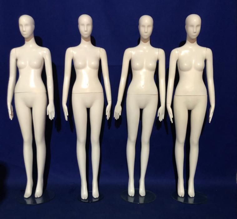 Cuatro maniquíes femeninos blancos de pie uno al lado del otro sobre un fondo azul