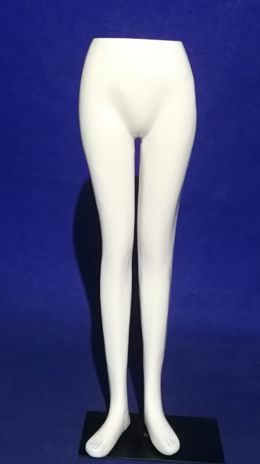 Un par de piernas de maniquí blancas sobre un fondo azul.