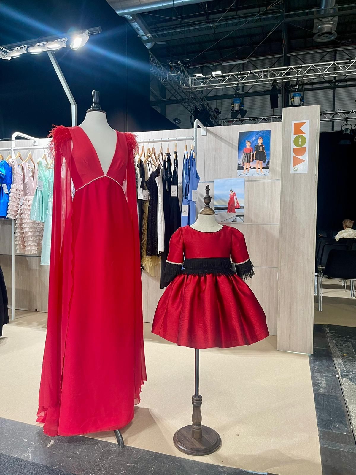 Un maniquí lleva un vestido rojo al lado del vestido rojo de un niño.