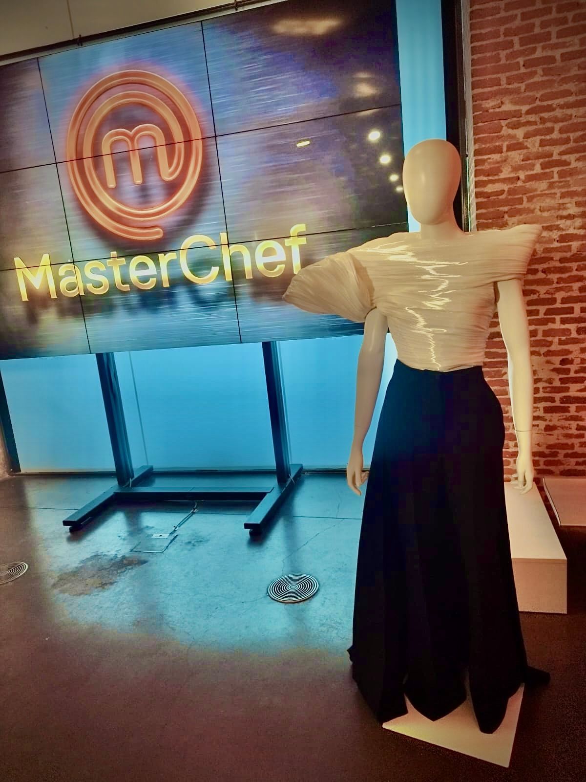 Un maniquí está parado frente a un cartel de maestro chef.