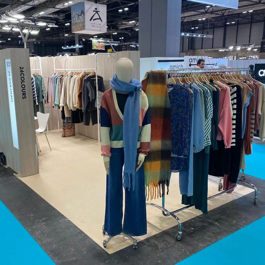 Un maniquí está parado delante de un perchero con ropa.