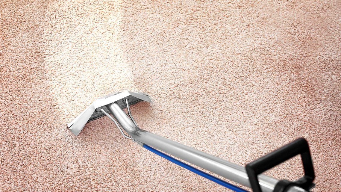 Herramienta limpiadora de alfombras que limpia una alfombra de color marrón claro.